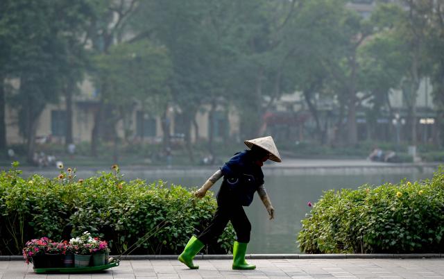 A worker drags flower pots along Hoan Kiem Lake in Hanoi on April 6, 2026. (Photo by Nhac NGUYEN / AFP)