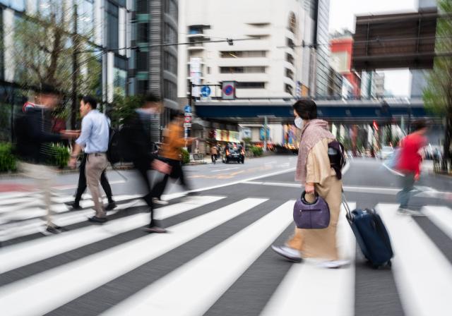 A woman walks across a street to a metro station at the end of the workday in Tokyo's Ginza district on April 6, 2026. (Photo by Andrew CABALLERO-REYNOLDS / AFP)