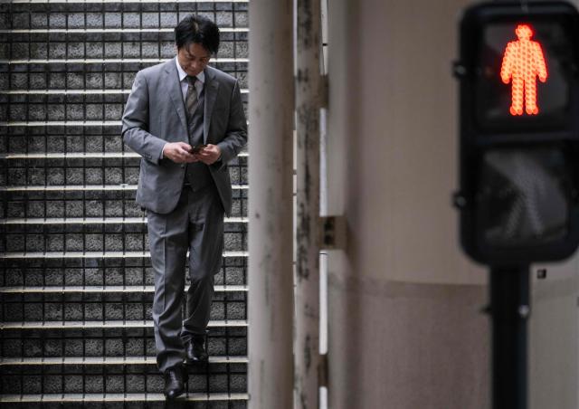 A businessman walks down a flight of stairs after crossing a highway near a metro station at the end of the workday in Tokyo's Ginza district on April 6, 2026. (Photo by Andrew CABALLERO-REYNOLDS / AFP)
