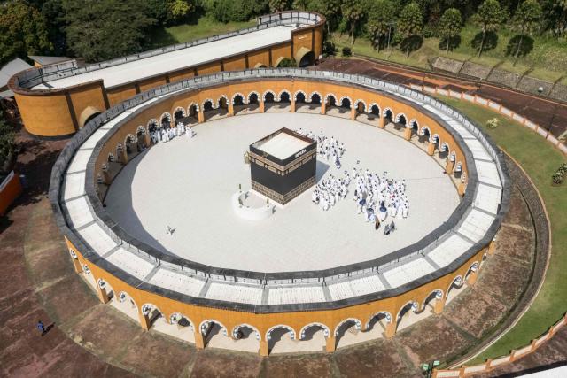 An aerial image shows prospective Indonesian pilgrims practicing circumambulation rituals around a replica of the Kaaba, Islam’s holiest shrine, during a training session at the Al Mahmudah Manasik Training Center (AMTC) in South Tangerang on April 5, 2026. The centre provides a simulated experience of Mecca’s pilgrimage sites ahead of the Hajj season in late May. Indonesia, home to the world’s largest Muslim population, has been allocated a Hajj quota of 221,000 pilgrims for 2026, but faces long waiting lists that can stretch for decades in some regions. (Photo by AFP)