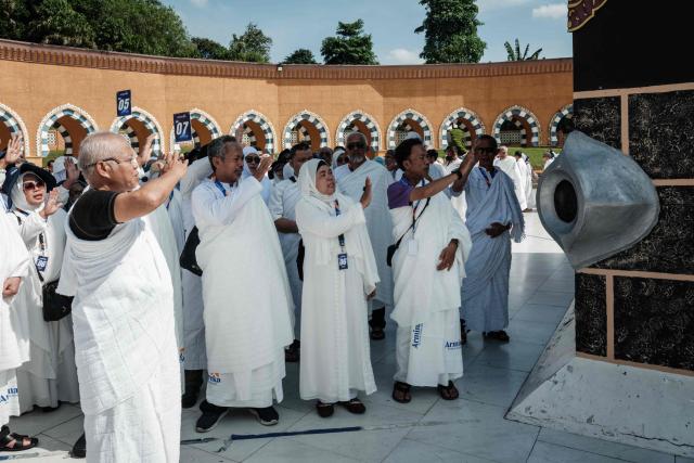 Prospective Indonesian pilgrims practice a ritual in front of a replica of the Hajar al-Aswad (the Black Stone) on a replica of the Kaaba, Islam’s holiest shrine, at the Al Mahmudah Manasik Training Center (AMTC), a Hajj training facility featuring replicas of key pilgrimage sites, in South Tangerang on April 5, 2026. The centre provides a simulated experience of Mecca’s pilgrimage sites ahead of the Hajj season in late May. Indonesia, home to the world’s largest Muslim population, has been allocated a Hajj quota of 221,000 pilgrims for 2026, but faces long waiting lists that can stretch for decades in some regions. (Photo by YASUYOSHI CHIBA / AFP)