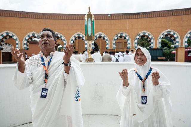 A couple practice a ritual at a replica of the Kaaba,Islam’s holiest shrine, after attending training at the Al Mahmudah Manasik Training Center (AMTC), a Hajj training facility featuring replicas of key pilgrimage sites, in South Tangerang on April 5, 2026. The centre provides a simulated experience of Mecca’s pilgrimage sites ahead of the Hajj season in late May. Indonesia, home to the world’s largest Muslim population, has been allocated a Hajj quota of 221,000 pilgrims for 2026, but faces long waiting lists that can stretch for decades in some regions. (Photo by YASUYOSHI CHIBA / AFP)