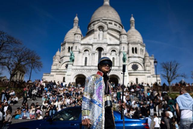 TOPSHOT - A pedestrian wearing reflective attire looks on near the entrance of the Sacre Coeur Basilica atop Montmartre hill, on Easter Monday in Paris on April 6, 2026. (Photo by Ian LANGSDON / AFP)