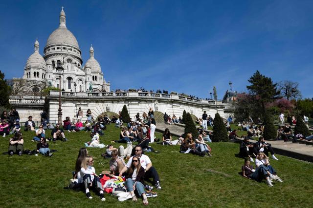 People enjoy the sunshine on the hillside leading to Sacre Coeur Basilica atop Montmartre hill, on Easter Monday in Paris on April 6, 2026. (Photo by Ian LANGSDON / AFP)