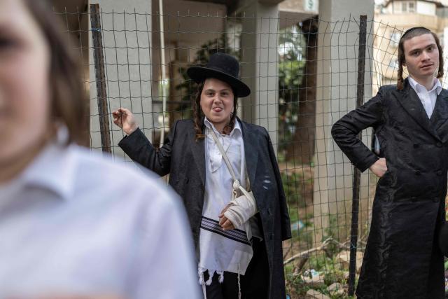 A boy sticks out his tongue while gathering with others to look at a building that was hit by an Iranian projectile attack in Bnei Brak in central Israel on April 6, 2026. Israeli strikes killed the intelligence chief of Iran's Revolutionary Guards, as the Islamic republic on April 6 defied threats from the US President to devastate civilian infrastructure if it does not reopen the Strait of Hormuz. (Photo by Ilia YEFIMOVICH / AFP) / 