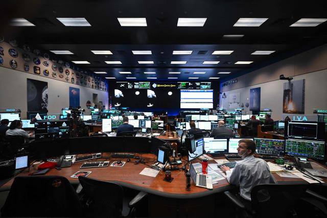 Artemis II flight controllers monitor the Orion spacecraft from the White Flight Control Room at Johnson Space Center in Houston, Texas, on April 6, 2026. The Artemis astronauts entered the final phase of their run-up to a lunar loop on Monday, a tipping point of sorts that means the Moon's gravity is now having a stronger pull on the spacecraft than Earth's. The Orion capsule will now whip around the Moon, setting the crew up to travel farther from our home planet than any human before. (Photo by RONALDO SCHEMIDT / AFP)