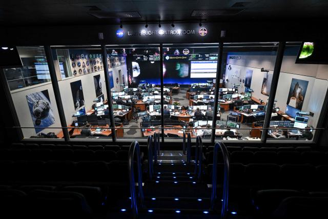 Artemis II flight controllers monitor the Orion spacecraft from the White Flight Control Room at Johnson Space Center in Houston, Texas, on April 6, 2026. The Artemis astronauts entered the final phase of their run-up to a lunar loop on Monday, a tipping point of sorts that means the Moon's gravity is now having a stronger pull on the spacecraft than Earth's. The Orion capsule will now whip around the Moon, setting the crew up to travel farther from our home planet than any human before. (Photo by RONALDO SCHEMIDT / AFP)