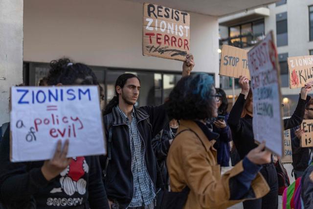 Israeli left-wing activists hold placards during a protest outside the US Embassy in Tel Aviv on April 6, 2026, against the ongoing war with Iran. The United States and Israel launched strikes against Iran on February 28, sparking swift retaliation by the Islamic republic which responded with missile attacks across the region. (Photo by Ilia YEFIMOVICH / AFP)