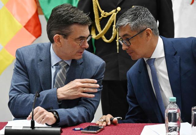 Bolivia's President Rodrigo Paz (L) speaks with his Economy Minister Jose Gabriel Espinoza during a press conference after the government revoked decrees on direct contracting and the awarding of public works contracts, at the Casa Grande del Pueblo, the seat of the Government Palace, in La Paz, on April 6, 2026. (Photo by Aizar RALDES / AFP)