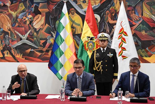 Bolivia's Presidency Minister Jose Luis Lupo (L) speaks next to Bolivia's President Rodrigo Paz (C) and Economy Minister Jose Gabriel Espinoza during a press conference after the government revoked decrees on direct contracting and the awarding of public works contracts, at the Casa Grande del Pueblo, the seat of the Government Palace, in La Paz, on April 6, 2026. (Photo by Aizar RALDES / AFP)