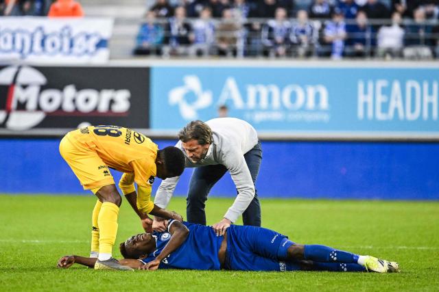 Gent's Ivorian forward Hyllarion Goore lies on the football pitch next to Gent's Belgian head coach Rik De Mil (up R) and Mechelen's Zimbabwean forward Bill Antonio (L) during the Belgian "Pro League" First Division football match between KAA Gent and KV Mechelen at the KAA Stadium in Ghent on April 6, 2026. (Photo by Tom Goyvaerts / BELGA / AFP) / Belgium OUT