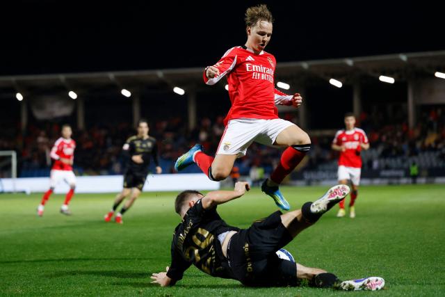 SL Benfica's Norwegian forward #21 Andreas Schjelderup jumps over Casa Pia's French forward #29 Jeremy Livolant during the Portuguese League football match between Casa Pia AC and SL Benfica at Rio Maior Municipal Stadium on April 6, 2026. (Photo by FILIPE AMORIM / AFP)