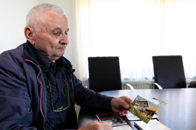 Juraj Pievac (70) looks at a photograph of his house, to which he returned after the liberation of occupied parts of Croatia in the village of Brodani near Karlovac on March 24, 2026. More than 30 years after the independence war, that left behind around 107,000 landmines and 470,000 unexploded ordnances, Croatia is declared mine-free, a historic milestone for the country. (Photo by MARKO PERKOV / AFP)