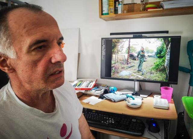 Mirsad Tokic, former deminer who lost his leg in a blast in 2007, while working in a remote village in the Adriatic coast hinterland, and his photo on the computer while working as a deminer, in his apartment in Zagreb,  on March 25, 2026. More than 30 years after the independence war, that left behind around 107,000 landmines and 470,000 unexploded ordnances, Croatia is declared mine-free, a historic milestone for the country. (Photo by Tina SMOLE / AFP)