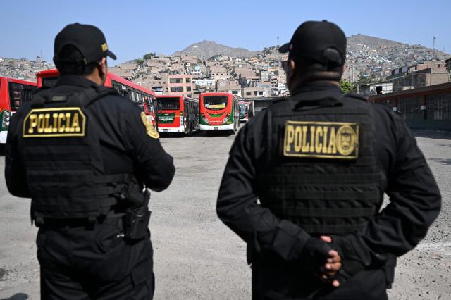 (FILES) Police officers stand guard at Santa Catalina bus station, which has been targeted by up to five criminal gangs, at the San Juan de Lurigancho district, east of Lima, on October 21, 2025. After a succession of short-lived presidencies, Peruvians will choose on April 12, 2026, from a record 35 candidates to elect their new leader, who will govern a country gripped by organized crime and chronic political instability. (Photo by Raul ARBOLEDA / AFP)