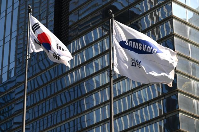 A South Korean national flag (L) and a Samsung flag (R) flutter outside the company's Seocho building in Seoul on April 7, 2026. Tech giant Samsung Electronics estimated on April 7 that its first quarter profit had soared 755 percent annually to a record high of 57.2 trillion won (37.9 billion USD), driven by strong sales of chips crucial for artificial intelligence. (Photo by Jung Yeon-je / AFP)