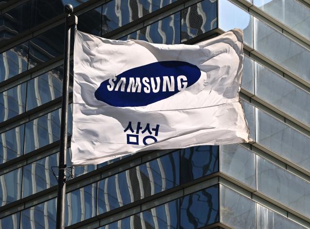 A Samsung flag flutters outside the company's Seocho building in Seoul on April 7, 2026. Tech giant Samsung Electronics estimated on April 7 that its first quarter profit had soared 755 percent annually to a record high of 57.2 trillion won (37.9 billion USD), driven by strong sales of chips crucial for artificial intelligence. (Photo by Jung Yeon-je / AFP)