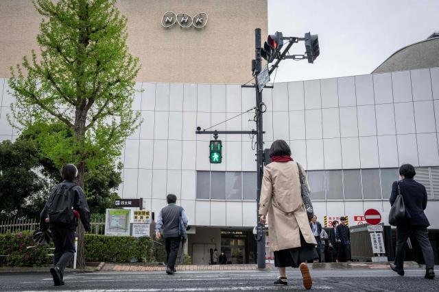 People cross a street outside the NHK Broadcasting Center in Tokyo on April 7, 2026. Iran freed a Japanese national held since January, Tokyo said on April 7, with Kyodo News reporting that the person was believed to be the Tehran bureau chief of broadcaster NHK. (Photo by Yuichi YAMAZAKI / AFP)
