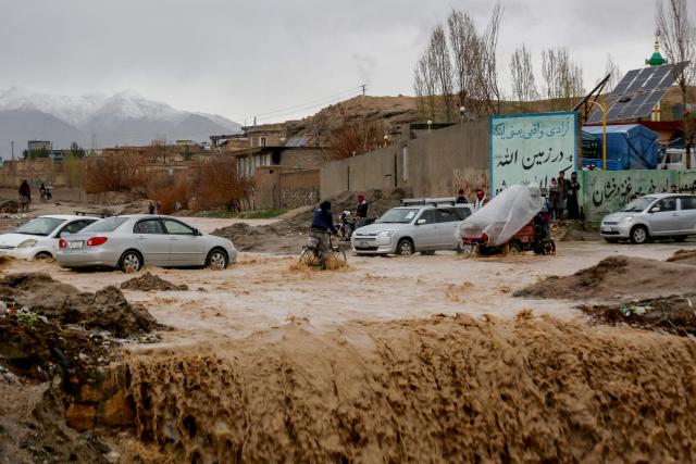 Afghan men look on as floodwaters inundate a street in Ghazni on April 6, 2026. Heavy rain and storms have killed at least 121 people over two weeks across Afghanistan and Pakistan, disaster officials in both countries said April 4. (Photo by Mohammad Faisal NAWEED / AFP)