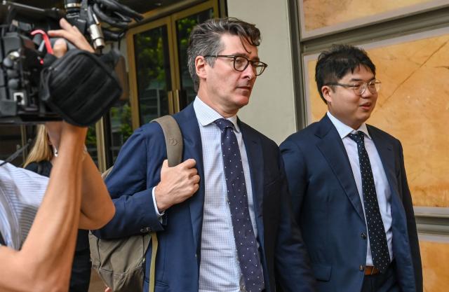 Singapore-based Bloomberg News senior executive editor John Fraher (C) and reporter Low De Wei (R) leave the Supreme court in Singapore on April 7, 2026. (Photo by Roslan RAHMAN / AFP)