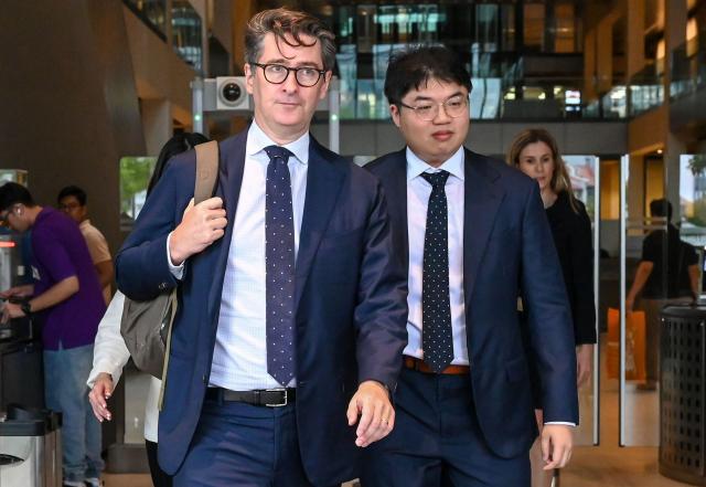 Singapore-based Bloomberg News senior executive editor John Fraher (L) and reporter Low De Wei (R) leave the Supreme court in Singapore on April 7, 2026. (Photo by Roslan RAHMAN / AFP)
