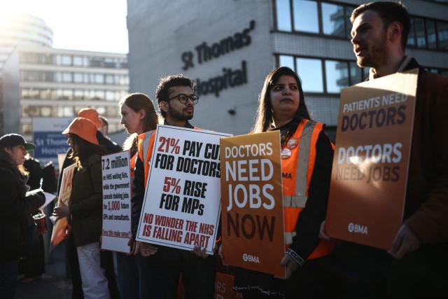 Staff members hold placards as they stand on a picket line during the first day of a six-day resident doctors' strike outside St Thomas' Hospital in central London on April 7, 2026. (Photo by Henry NICHOLLS / AFP)