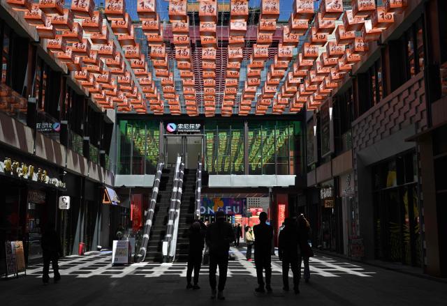 People visit a shopping center in Beijing on April 7, 2026. (Photo by ADEK BERRY / AFP)