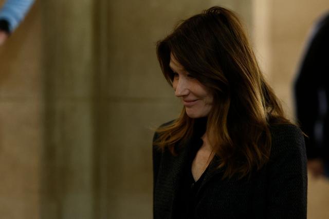 Carla Bruni-Sarkozy (C), wife of France's former president Nicolas Sarkozy, leaves the courtroom during the appeal trial of her husband over charges he sought Libyan financing for his 2007 election, at the Palais de Justice courthouse in Paris on April 7, 2026. The Paris Criminal Court in September 2025 convicted Sarkozy of criminal conspiracy and handed him a 5-year prison sentence over what it said was a scheme to acquire funding from Muammar Gaddafi's Libya for his 2007 presidential run that saw him elected. The right-wing politician -- who has denied any wrongdoing -- entered a Paris jail in October 2025, serving 20 days before he was released under judicial supervision. (Photo by Kenzo TRIBOUILLARD / AFP)