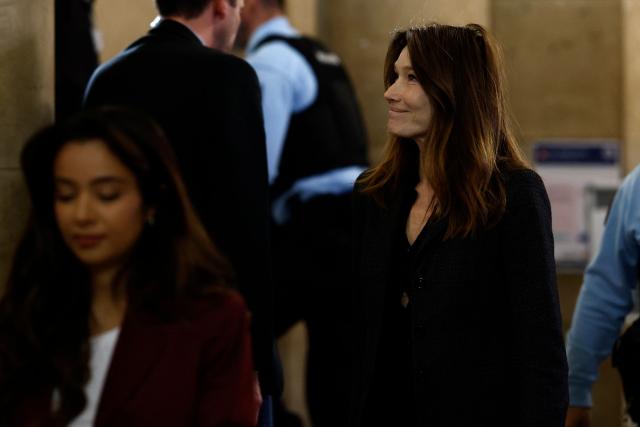Carla Bruni-Sarkozy (C), wife of France's former president Nicolas Sarkozy, leaves the courtroom during the appeal trial of her husband over charges he sought Libyan financing for his 2007 election, at the Palais de Justice courthouse in Paris on April 7, 2026. The Paris Criminal Court in September 2025 convicted Sarkozy of criminal conspiracy and handed him a 5-year prison sentence over what it said was a scheme to acquire funding from Muammar Gaddafi's Libya for his 2007 presidential run that saw him elected. The right-wing politician -- who has denied any wrongdoing -- entered a Paris jail in October 2025, serving 20 days before he was released under judicial supervision. (Photo by Kenzo TRIBOUILLARD / AFP)