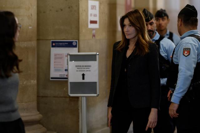 Carla Bruni-Sarkozy (C), wife of France's former president Nicolas Sarkozy, leaves the courtroom during the appeal trial of her husband over charges he sought Libyan financing for his 2007 election, at the Palais de Justice courthouse in Paris on April 7, 2026. The Paris Criminal Court in September 2025 convicted Sarkozy of criminal conspiracy and handed him a 5-year prison sentence over what it said was a scheme to acquire funding from Muammar Gaddafi's Libya for his 2007 presidential run that saw him elected. The right-wing politician -- who has denied any wrongdoing -- entered a Paris jail in October 2025, serving 20 days before he was released under judicial supervision. (Photo by Kenzo TRIBOUILLARD / AFP)