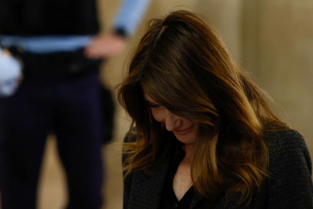 Carla Bruni-Sarkozy (C), wife of France's former president Nicolas Sarkozy, leaves the courtroom during the appeal trial of her husband over charges he sought Libyan financing for his 2007 election, at the Palais de Justice courthouse in Paris on April 7, 2026. The Paris Criminal Court in September 2025 convicted Sarkozy of criminal conspiracy and handed him a 5-year prison sentence over what it said was a scheme to acquire funding from Muammar Gaddafi's Libya for his 2007 presidential run that saw him elected. The right-wing politician -- who has denied any wrongdoing -- entered a Paris jail in October 2025, serving 20 days before he was released under judicial supervision. (Photo by Kenzo TRIBOUILLARD / AFP)