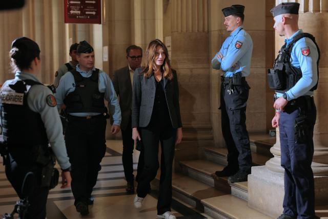 Carla Bruni-Sarkozy (C), wife of France's former president Nicolas Sarkozy, returns to the courtroom during the appeal trial of her husband over charges he sought Libyan financing for his 2007 election, at the Palais de Justice courthouse in Paris on April 7, 2026. The Paris Criminal Court in September 2025 convicted Sarkozy of criminal conspiracy and handed him a 5-year prison sentence over what it said was a scheme to acquire funding from Muammar Gaddafi's Libya for his 2007 presidential run that saw him elected. The right-wing politician -- who has denied any wrongdoing -- entered a Paris jail in October 2025, serving 20 days before he was released under judicial supervision. (Photo by Thomas SAMSON / AFP)