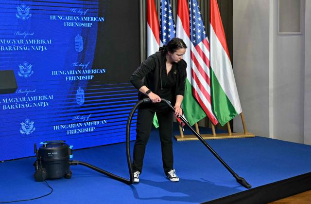 A woman cleans the carpet in preparation of a joint press conference of Hungary's Prime Minister with the US Vice President at the Carmelite Monastery of Buda in Budapest, Hungary, on April 7, 2026. US Vice President JD Vance arrived in Hungary to deliver US President Donald Trump's support to his ally, nationalist Prime Minister Viktor Orban, ahead of tightly contested parliamentary elections scheduled for April 12, 2026. (Photo by Attila KISBENEDEK / AFP)