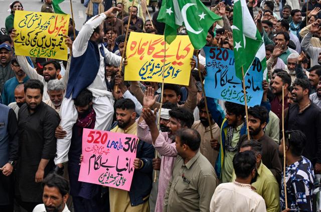 Auto rickshaw drivers hold Pakistan's national flag and shout slogans during an anti-government protest against rising fuel prices triggered by the Middle East war, in Lahore on April 7, 2026. State-run public transport in Pakistan's capital and most populous province will be free for the coming month, officials said on April 3, after the government drastically raised fuel prices due to the Iran war. The announcement came after street protests and long queues of motorcycles at fuel stations triggered by a late-night decision to impose a 42.7-percent rise in the price of petrol to 485 rupees (US$1.74) per litre. (Photo by Arif ALI / AFP)