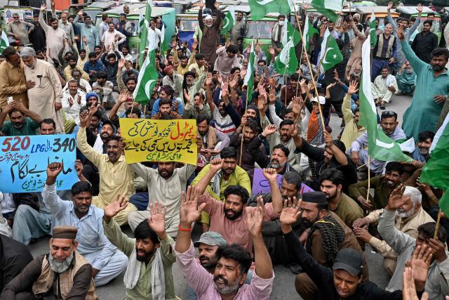 Auto rickshaw drivers hold Pakistan's national flag and shout slogans during an anti-government protest against rising fuel prices triggered by the Middle East war, in Lahore on April 7, 2026. State-run public transport in Pakistan's capital and most populous province will be free for the coming month, officials said on April 3, after the government drastically raised fuel prices due to the Iran war. The announcement came after street protests and long queues of motorcycles at fuel stations triggered by a late-night decision to impose a 42.7-percent rise in the price of petrol to 485 rupees (US$1.74) per litre. (Photo by Arif ALI / AFP)