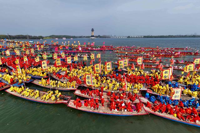 People take part in the Taizhou Jiangyan Qintong Boat Festival on Qinhu lake in Taizhou, in China’s eastern Jiangsu province on April 6, 2026. Thousands took part in the annual festival, which occurs during the Qingming, or Tomb Sweeping festival holiday. (Photo by CN-STR / AFP) / China OUT
