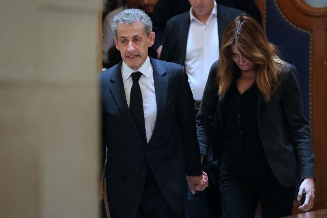 Former France's President Nicolas Sarkozy (L) and his wife Carla Bruni-Sarkozy leave the courtroom following a recess in his appeal trial over charges he sought Libyan financing for his 2007 election, at the Palais de Justice courthouse in Paris on April 7, 2026. The Paris Criminal Court in September 2025 convicted Sarkozy of criminal conspiracy and handed him a 5-year prison sentence over what it said was a scheme to acquire funding from Muammar Gaddafi's Libya for his 2007 presidential run that saw him elected. The right-wing politician -- who has denied any wrongdoing -- entered a Paris jail in October 2025, serving 20 days before he was released under judicial supervision. (Photo by Thomas SAMSON / AFP)
