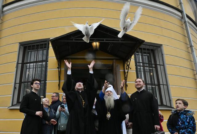 Metropolitan of St. Petersburg and Ladoga Barsanuphius (R) and Orthodox priests release white doves after a service marking the Holiday of Annunciation in front of the Annunciation Church in Saint Petersburg on April 7, 2026. In Christianity, Annunciation celebrates the revelation to the Virgin Mary that she would bear a son, Jesus. (Photo by Olga MALTSEVA / AFP)