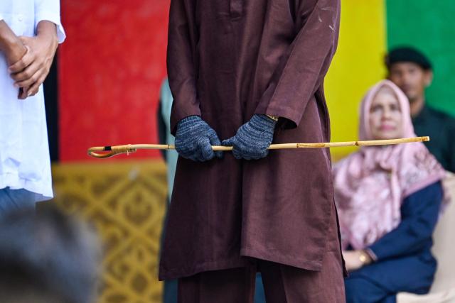 A member of Aceh's Sharia police wields a rattan stick during a public flogging in Banda Aceh on April 7, 2026. A couple was publicly flogged in Indonesia's staunchly Islamic Aceh province on April 7 for having sex outside of marriage, an AFP reporter witnessed, in the country's only region to apply a version of Sharia law. Sexual relations between unmarried people are outlawed in Aceh. (Photo by CHAIDEER MAHYUDDIN / AFP)
