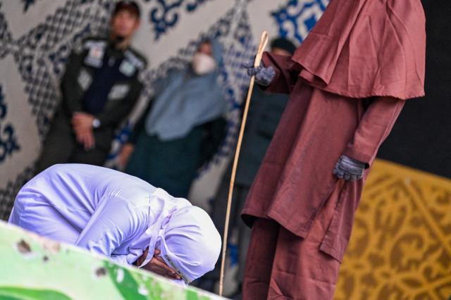 A woman (L) reacts during a public flogging held by Aceh's Sharia police in Banda Aceh on April 7, 2026. A couple was publicly flogged in Indonesia's staunchly Islamic Aceh province on April 7 for having sex outside of marriage, an AFP reporter witnessed, in the country's only region to apply a version of Sharia law. Sexual relations between unmarried people are outlawed in Aceh. (Photo by CHAIDEER MAHYUDDIN / AFP)