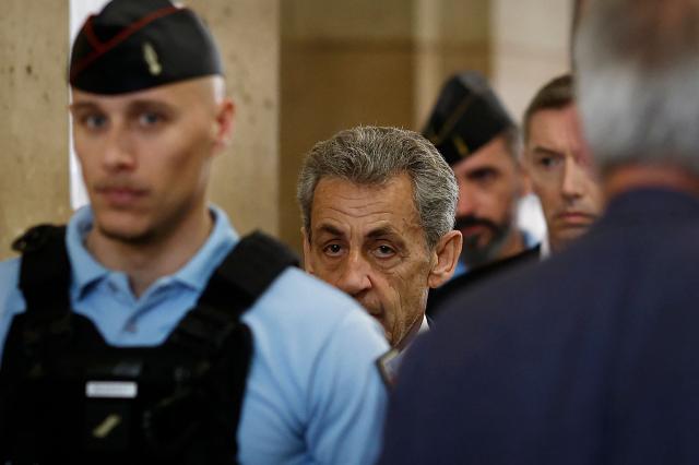 TOPSHOT - Former France's President Nicolas Sarkozy (C) returns to the courtroom following a recess in his appeal trial over charges he sought Libyan financing for his 2007 election, at the Palais de Justice courthouse in Paris on April 7, 2026. The Paris Criminal Court in September 2025 convicted Sarkozy of criminal conspiracy and handed him a 5-year prison sentence over what it said was a scheme to acquire funding from Muammar Gaddafi's Libya for his 2007 presidential run that saw him elected. The right-wing politician -- who has denied any wrongdoing -- entered a Paris jail in October 2025, serving 20 days before he was released under judicial supervision. (Photo by Kenzo TRIBOUILLARD / AFP)