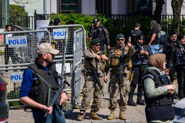 A police official gestures as he stands alert near The Israeli Consulate in Istanbul on April 7, 2026, following a shootout between gunmen and police. One gunman was killed and two others were wounded in a shootout with police outside the Israeli consulate in Istanbul, the local governor said, adding two officers were lightly wounded (Photo by Yasin AKGUL / AFP)