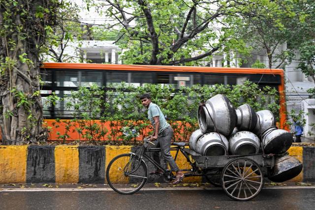 A man pulls his rickshaw cart laden with utensils as it rains in the old quarters of Delhi on April 7, 2026. (Photo by Sajjad HUSSAIN / AFP)
