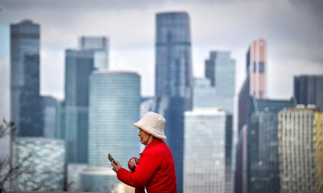 A Chinese tourist walks at the observation point at Vorobyovy Hills in front of the buildings of the Moscow International Business Centre (Moskva City) in Moscow on April 7, 2026. (Photo by Alexander NEMENOV / AFP)