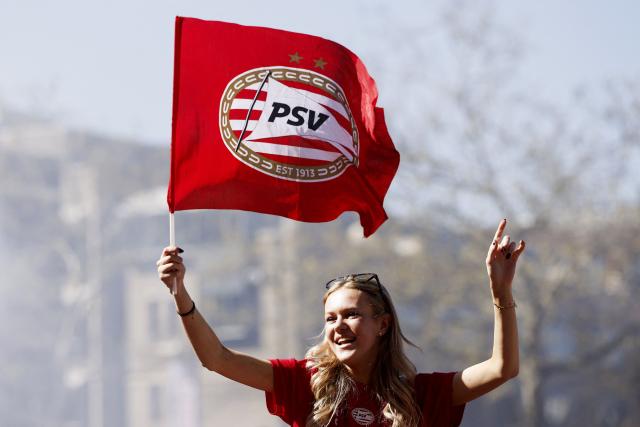 A PSV Eindhoven's supporter holds the club's flag as she celebrates third consecutive Eredivisie football national title at the Stadhuisplein in Eindhoven on April 7, 2026. PSV Eindhoven were crowned Dutch champions for the 27th time on April 5, 2026, with five matches left of the season after second-placed Feyenoord's 0-0 draw with Volendam. (Photo by Sem van der Wal / ANP / AFP) / Netherlands OUT