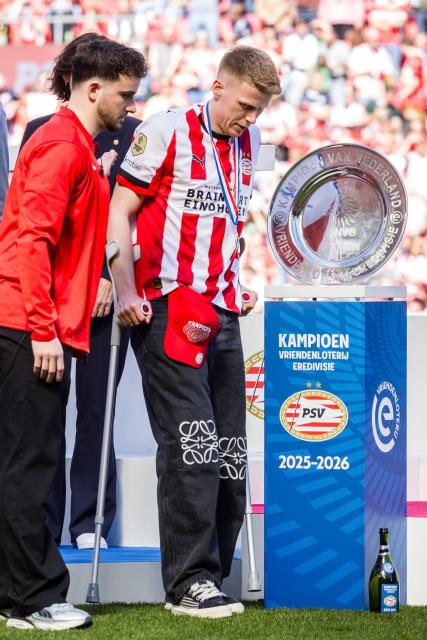 PSV Eindhoven's Captain Jerdy Schouten (R) looks at the trophy of the Netherlands' 2025-2026 Eredivisie football national season during celebrations for their third consecutive championship at the Stadhuisplein in Eindhoven on April 7, 2026. PSV Eindhoven were crowned Dutch champions for the 27th time on April 5, 2026, with five matches left of the season after second-placed Feyenoord's 0-0 draw with Volendam. (Photo by ROB ENGELAAR / ANP / AFP) / Netherlands OUT