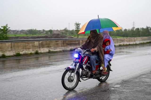A man rides a motorbike with his family along a road during rainfall in Peshawar on April 7, 2026. Heavy rain, storms, and floods have battered Afghanistan and neighbouring Pakistan for more than two weeks, killing at least 188 people, disaster officials in both countries said on April 7, 2026. (Photo by Abdul MAJEED / AFP)