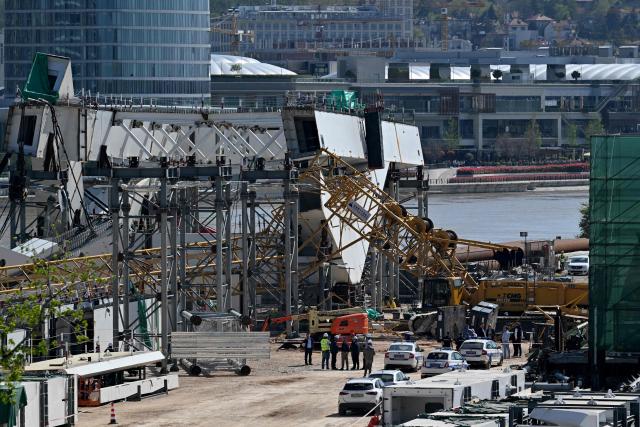 Police officers and construction workers stand by the scene where a crane collapsed at the construction site of a new bridge, on the banks of the River Sava in Belgrade on April 7, 2026. The collapsing of the 350-ton metal structure left one person dead while three others were injured, according to the Serbian Interior Ministry and Serbian media. The circumstances surrounding the incident are currently under investigation by the authorities. (Photo by Andrej ISAKOVIC / AFP)