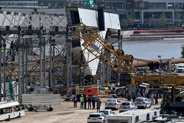Police officers and construction workers stand by the scene where a crane collapsed at the construction site of a new bridge, on the banks of the River Sava in Belgrade on April 7, 2026. The collapsing of the 350-ton metal structure left one person dead while three others were injured, according to the Serbian Interior Ministry and Serbian media. The circumstances surrounding the incident are currently under investigation by the authorities. (Photo by Andrej ISAKOVIC / AFP)