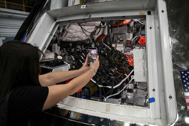 A journalist takes pictures of the Orion spacecraft mockup on April 7, 2026 at Johnson Space Center in Houston, Texas. After completing their lunar flyby -- breaking the record for distance from Earth -- the Artemis II crew is bound for home, with splashdown due in the Pacific off the coast of California late April 10. (Photo by RONALDO SCHEMIDT / AFP)